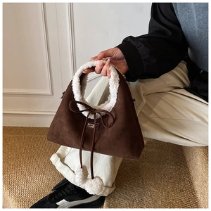 Detail of suede handbag with faux shearling trim and decorative plush pom-poms