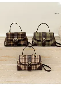 Detail of plaid handbags in brown, green and pink with leather trim on stone steps