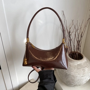 Sac croissant marron foncé brillant avec détails dorés et bandoulière minimaliste