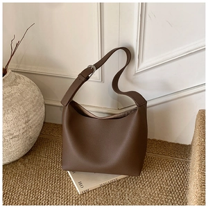 Close-up of dark brown lychee grain leather texture and metallic buckle on hobo bag