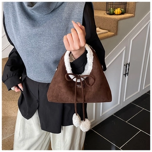 Close-up of brown suede handbag with white faux fur trim and cute white pompom charm