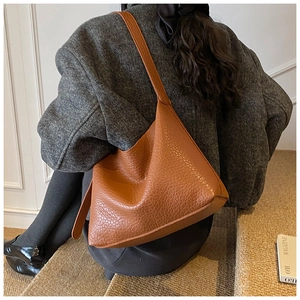 Sac hobo en cuir grainé caramel avec bandoulière porté dans une ambiance d'automne