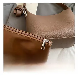 Macro detail of brown leather bucket bag showing silver zipper and pebble grain texture