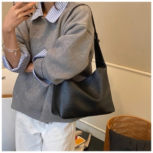 Vue détaillée du sac hobo en cuir noir grainé porté par un mannequin en intérieur