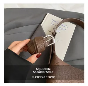 Detail of adjustable shoulder strap on dark brown litchi pattern leather bucket bag