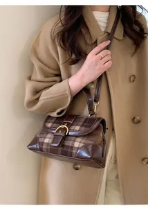 Close-up of retro brown plaid handbag with leather stitching and gold buckle detail