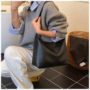Détail du sac à bandoulière en cuir noir avec texture litchi pour le trajet quotidien