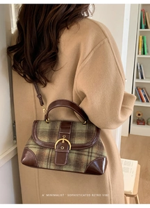 Detail of retro plaid handbag with gold buckle and leather trim on an autumn coat