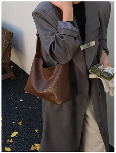 Gros plan d'un sac cabas en cuir marron texturé porté par un mannequin en blazer gris
