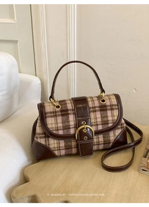 Macro shot of retro plaid handbag with brown leather trim and gold buckle detailing