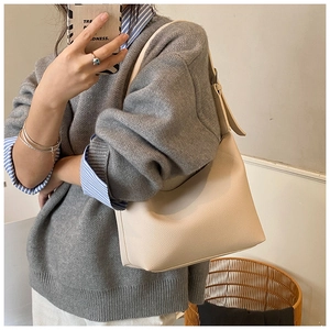 Detail of beige lychee textured leather bucket bag with wide adjustable shoulder strap