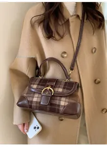 Close-up of retro plaid handbag with brown leather trim and golden buckle detail