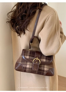 Detail of vintage plaid handbag with gold horseshoe buckle worn on a wool coat