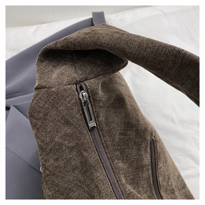 Detail of dark brown canvas shoulder bag showing zipper closure and woven texture