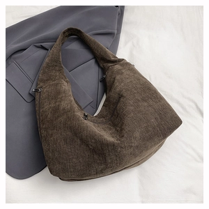 Close-up of deep brown textured canvas shoulder bag with functional metal zippers