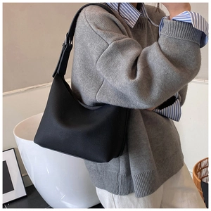 Detail of black pebbled leather tote bag with adjustable strap worn by a model