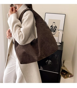 Detail of a large brown hobo canvas shoulder bag worn by model showing texture and capacity