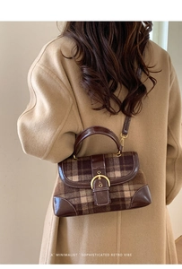 Close-up of retro plaid handbag with brown leather trim and golden horseshoe buckle detail