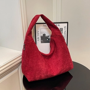 Burgundy corduroy hobo shoulder bag with wide strap and silver zipper on a table