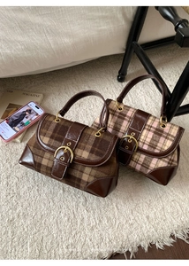 Close-up of retro plaid handbags with brown leather trim and golden horseshoe buckles