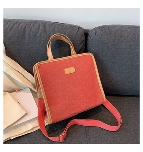 Detail of vintage square canvas handbag with brown leather trim on gray fabric sofa
