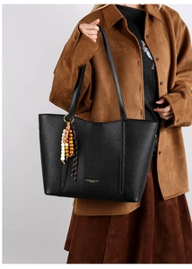 Close-up of black litchi pattern leather tote bag with gold lettering and colorful tassel