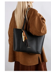 Detail of black pebbled leather tote bag with colorful wooden beads and embossed logo