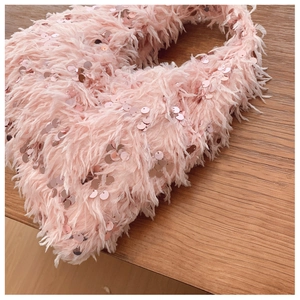 Detailed close-up of pink fluffy feather handbag with sparkling sequins and chain strap