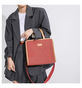 Detail of red canvas tote with leather trim and wide shoulder strap shown on model