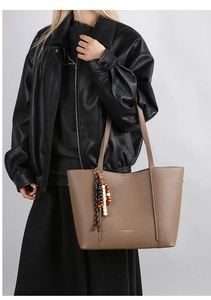 Detail of taupe pebbled leather tote with gold branding and wooden bead tassel