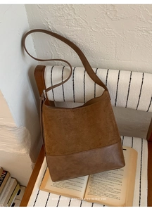 Gros plan du sac hobo en daim marron avec bandoulière en cuir sur chaise rétro