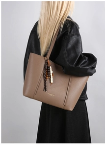Detail of brown litchi pattern tote bag with beaded tassel and gold fashion lettering