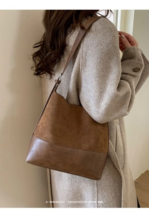 Gros plan du sac bandoulière en daim marron porté avec une texture rétro minimaliste