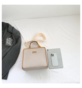 Overhead view of square canvas handbag with brown leather trim and wide fabric strap