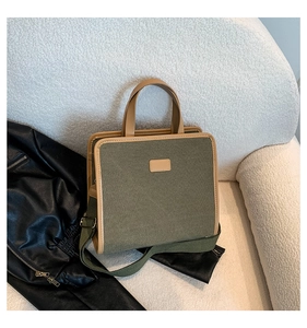 Detail of square army green canvas crossbody bag with tan leather trim on soft surface