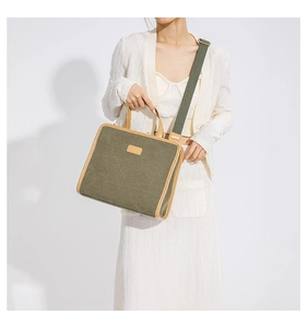 Detail of olive green canvas crossbody bag with brown leather trim worn by model