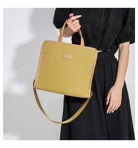 Detail of mustard yellow canvas messenger bag with leather handles and shoulder strap