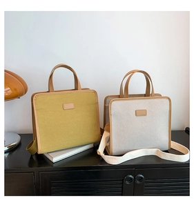 Detail of square canvas handbags in mustard green and beige with leather trim and wide straps
