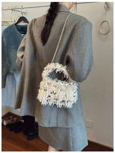 Detail of white faux fur handbag with sparkling sequins and silver chain strap in style