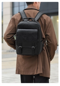 Detail of black textured leather backpack with metal buckles and wide shoulder straps