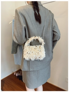 Detail of furry beige handbag with sequins and silver chain strap on a model