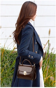 Brown leather handbag detail featuring a gold metal lock and a top handle for elegant styling