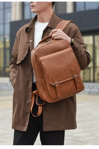 Brown leather commuter backpack with metal buckles shown in an urban street style setting