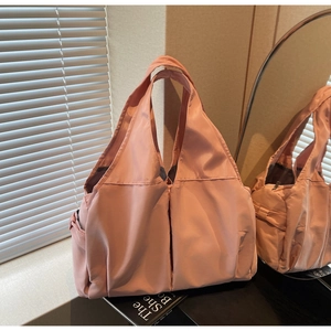 Detail of mauve nylon tote bag showing the glossy fabric texture and side pocket