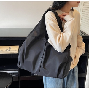 Detailed view of large black nylon shoulder bag with wide strap on model for daily commute