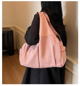 Rear view of a light pink Hobo bag showing the wide strap and spacious side pocket