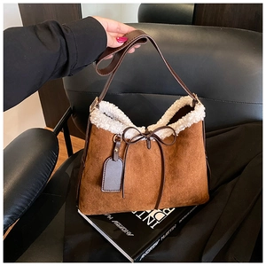 Detailansicht der braunen Wildledertasche mit weißem Lammfellbesatz und Schleifendekor