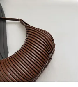 Détail du tissu plissé marron et de l'anneau de réglage en métal sur le sac à bandoulière
