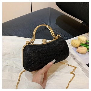 Detail of black glitter evening clutch with gold metal handle and crystal clasp closure