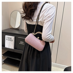 Close-up of pink sequined evening clutch bag with gold handle and chain strap worn by model